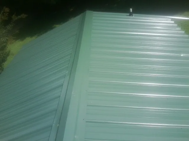 New green metal panels meeting at the ridge of a roof — Flat Roof Repair work by our crew in Lawton