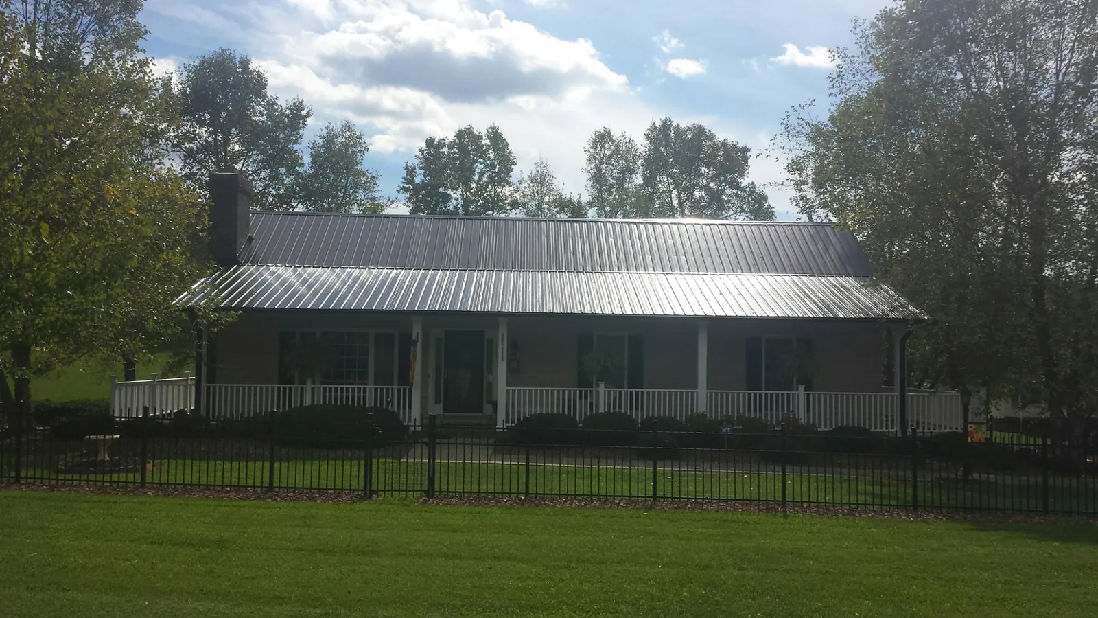 Gray metal roof on a brick ranch with a full width front porch — Gutter Guard Installation work by our crew in Lawton